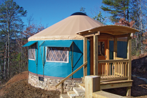 Small Pacific Yurt with a light blue tarp and a wooden front door porch.