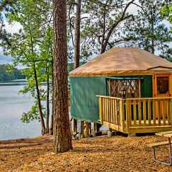 Pacific Yurt with a green tarp on the side of a lake.