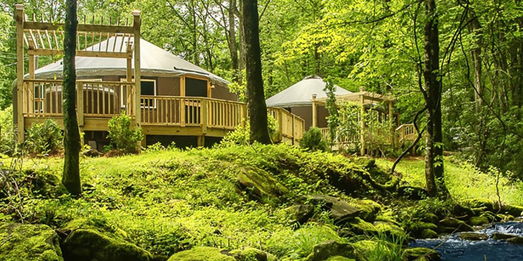 Yurt in the woods with a river running in front.