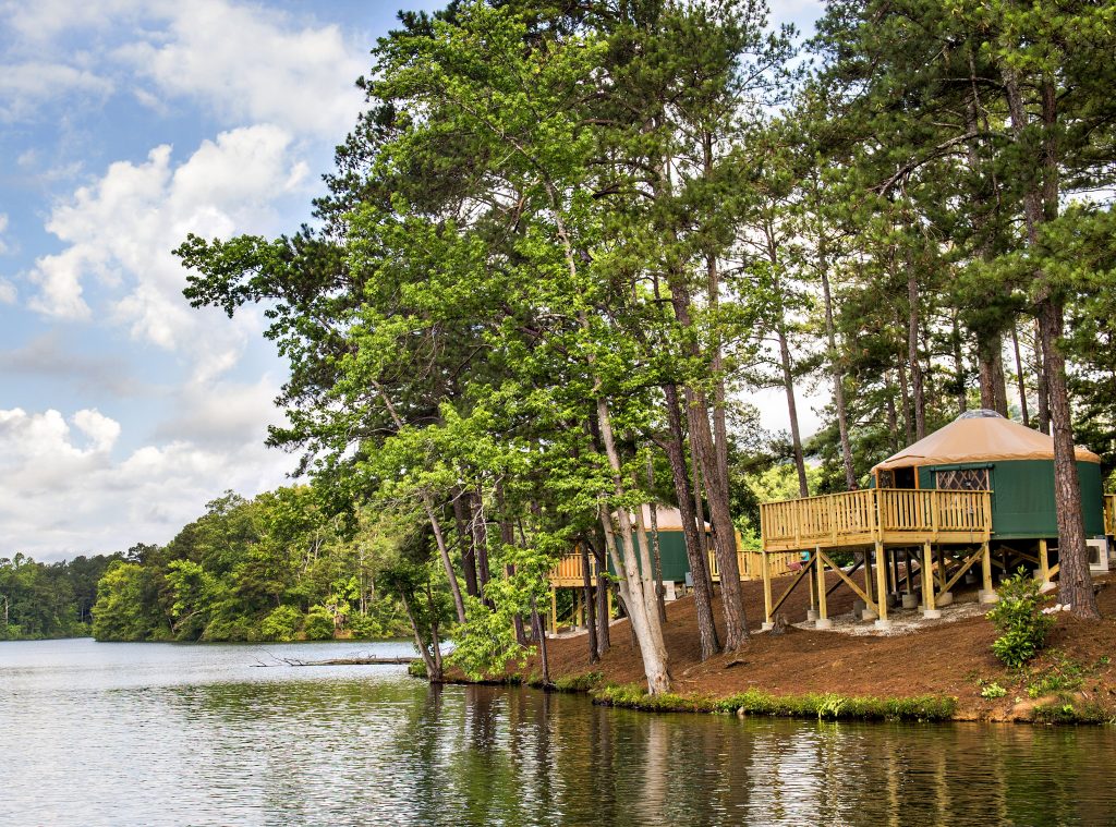 Yurt on an elevated platform with a balcony on the side of a lake.