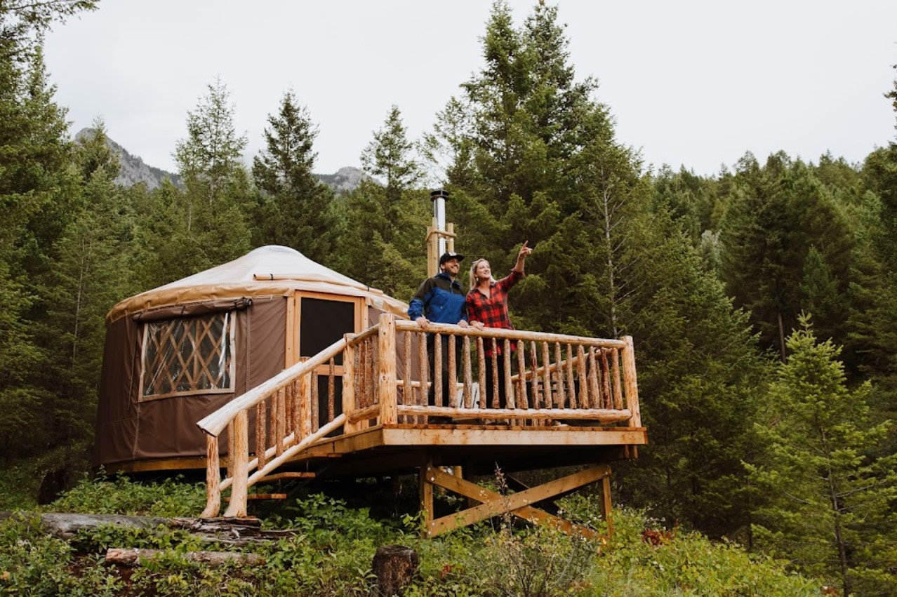 Two people standing on a deck outside of a Pacific Yurt at Radius Retreat.