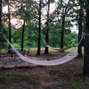 Two woven hammocks strung between trees at a campground.