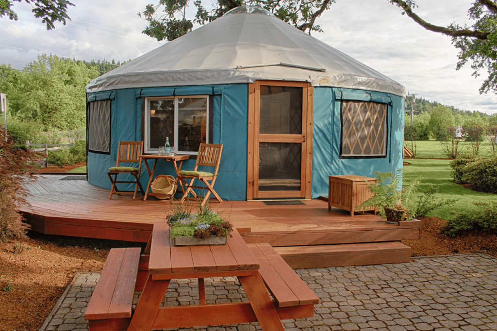 05-glamping-business - Pacific Yurts Pacific Yurt with a light blue canvas, a wooden deck surrounding the structure, and a picnic table outside.