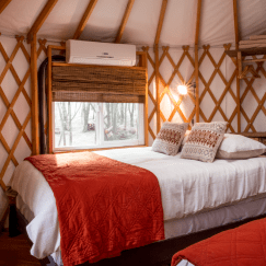 Two full sized beds with white sheets and red blankets inside a Pacific Yurt.