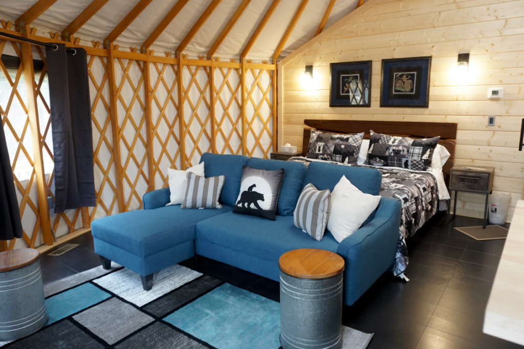 Blue couch at the foot of a queen size bed in a Pacific Yurt.