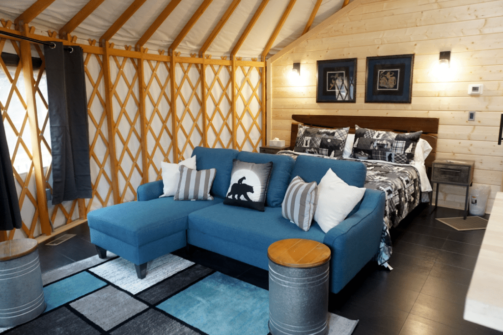 Blue couch at the foot of a queen size bed in a Pacific Yurt.