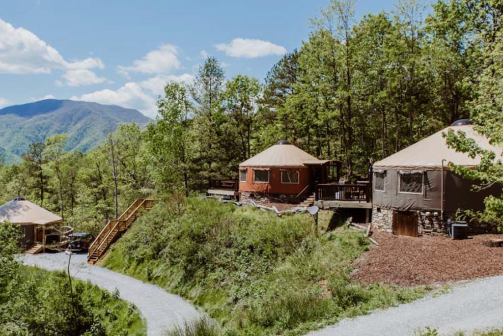 three yurts on winding road in forest.